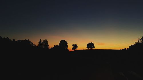 Silhouette trees on landscape against sky during sunset