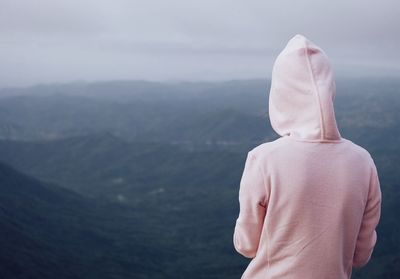 Rear view of woman standing by mountains against sky