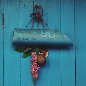 Close-up of blue door and white metal hanging on wall