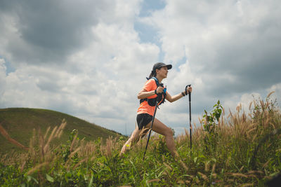 Full length of woman exercising on field against sky