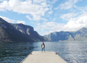 Woman standing on pier over lake against mountains