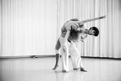 Mid adult couple dancing against curtain at dance studio