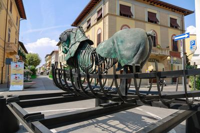 Statue amidst buildings in city against sky