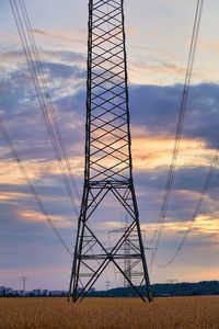 Low angle view of electricity pylon on field against sky