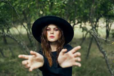 Portrait of young woman standing against trees