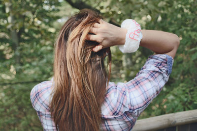 Midsection of the back of a woman holding hair in woodland