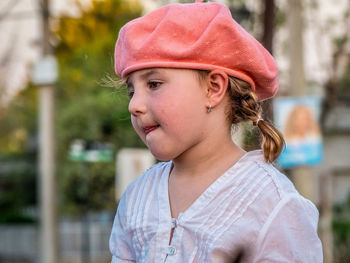 Close-up of thoughtful girl wearing flat cap against trees