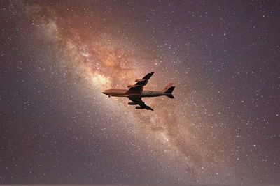 Low angle view of airplane flying against sky at night