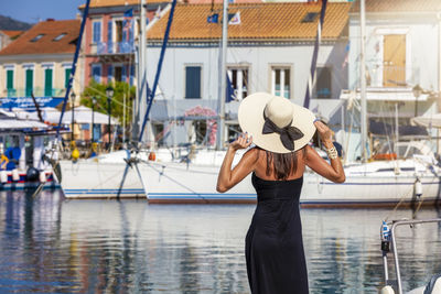 Rear view of woman wearing hat standing at harbor