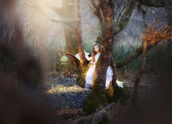 Pretty little prinzess with long hair in a dark fairy forest, playing the flute 