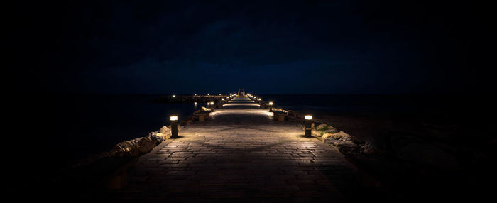 View of illuminated pier at night