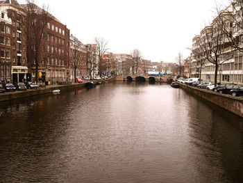 Canal amidst buildings in city against clear sky