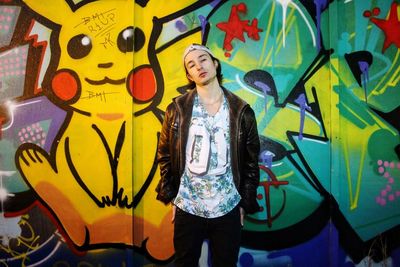 Portrait of young woman standing against graffiti