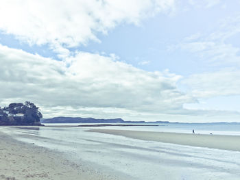 View of calm beach against cloudy sky