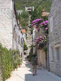 Rear view of woman walking on footpath amidst buildings