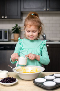 Little smiling cute girl mixing ingredients for baking homemade muffins. child cooking in kitchen.