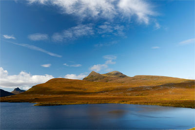 Scenic view of lake by mountains against sky