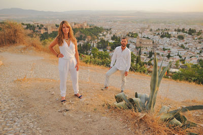 Portrait of couple standing on cobbled road during sunset