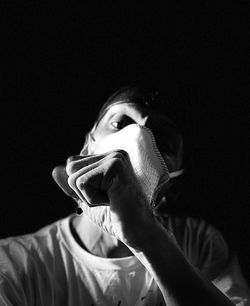 Portrait of young man holding cigarette against black background