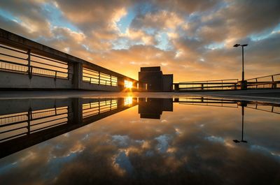 Bridge over river against cloudy sky at sunset