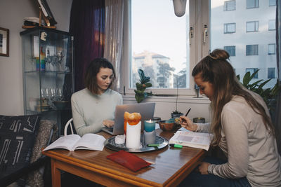 Young female students studying together in college dorm room