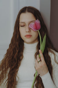 Portrait of a young girl with closed eyes, long hair and a tulip flower