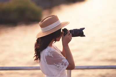 Woman photographing water by railing
