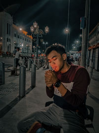 Young woman sitting on illuminated city at night