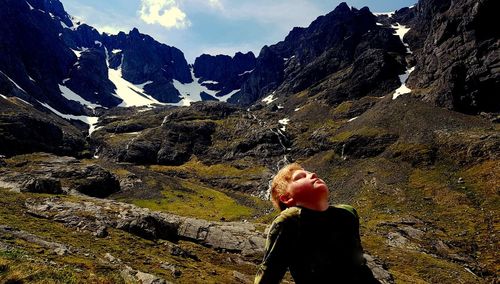 Girl with head back relaxing against mountain and sky