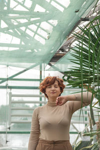 A beautiful plus size girl enjoying standing among the green plants of the greenhouse.