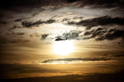 Low angle view of silhouette helicopter against sky during sunset