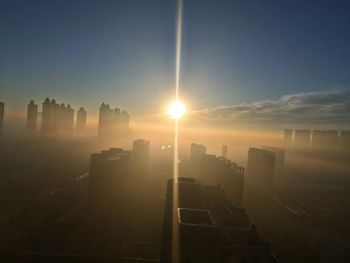 Modern buildings in city against sky during sunset