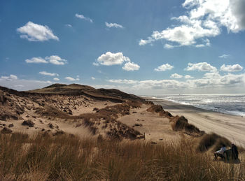 Scenic view of beach against cloudy sky