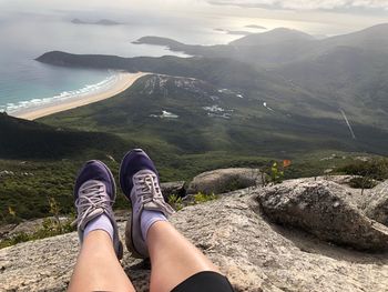 Low section of woman relaxing on cliff 