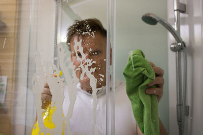 Mature man cleaning bathroom glass
