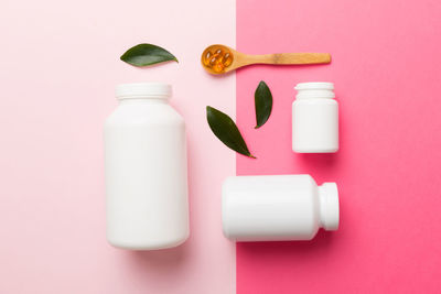 High angle view of pills spilling from bottle against yellow background