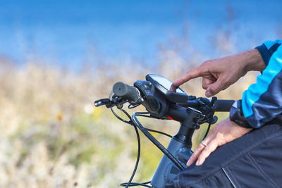 Close-up of hand holding motorcycle against sky