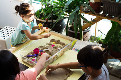 High angle view of siblings playing with sand