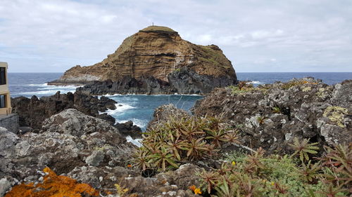 Rock formation by sea against sky