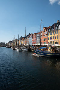 Sailboats moored on river by buildings against sky in city