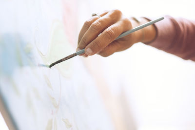 Cropped hand of artist drawing on canvas