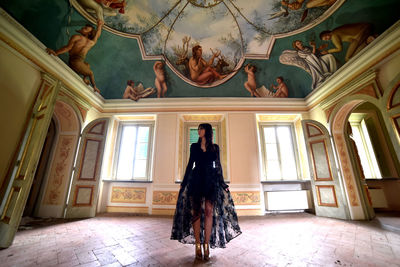 Full length of woman standing in corridor of historic building