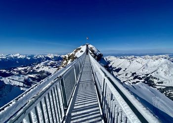 High angle view of snow covered mountain against blue sky