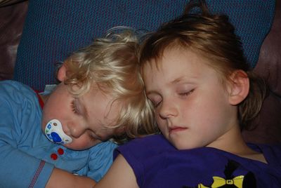 Cute siblings sleeping on bed