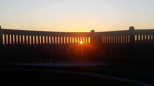 Silhouette bridge against clear sky during sunset