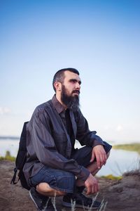 Young man sitting against clear sky