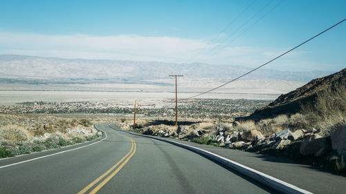 Road leading towards mountain against sky