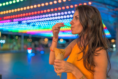 Midsection of woman holding colorful while standing at night