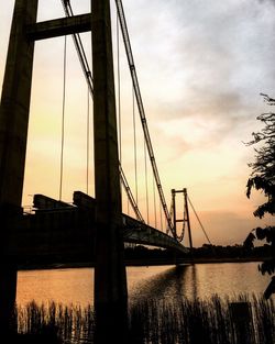 Bridge over river against cloudy sky