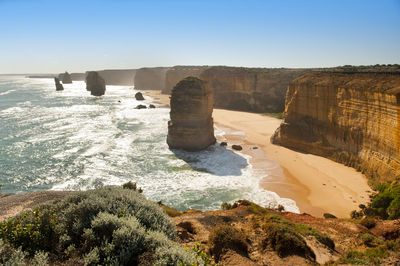 Rock formations on beach against clear sky